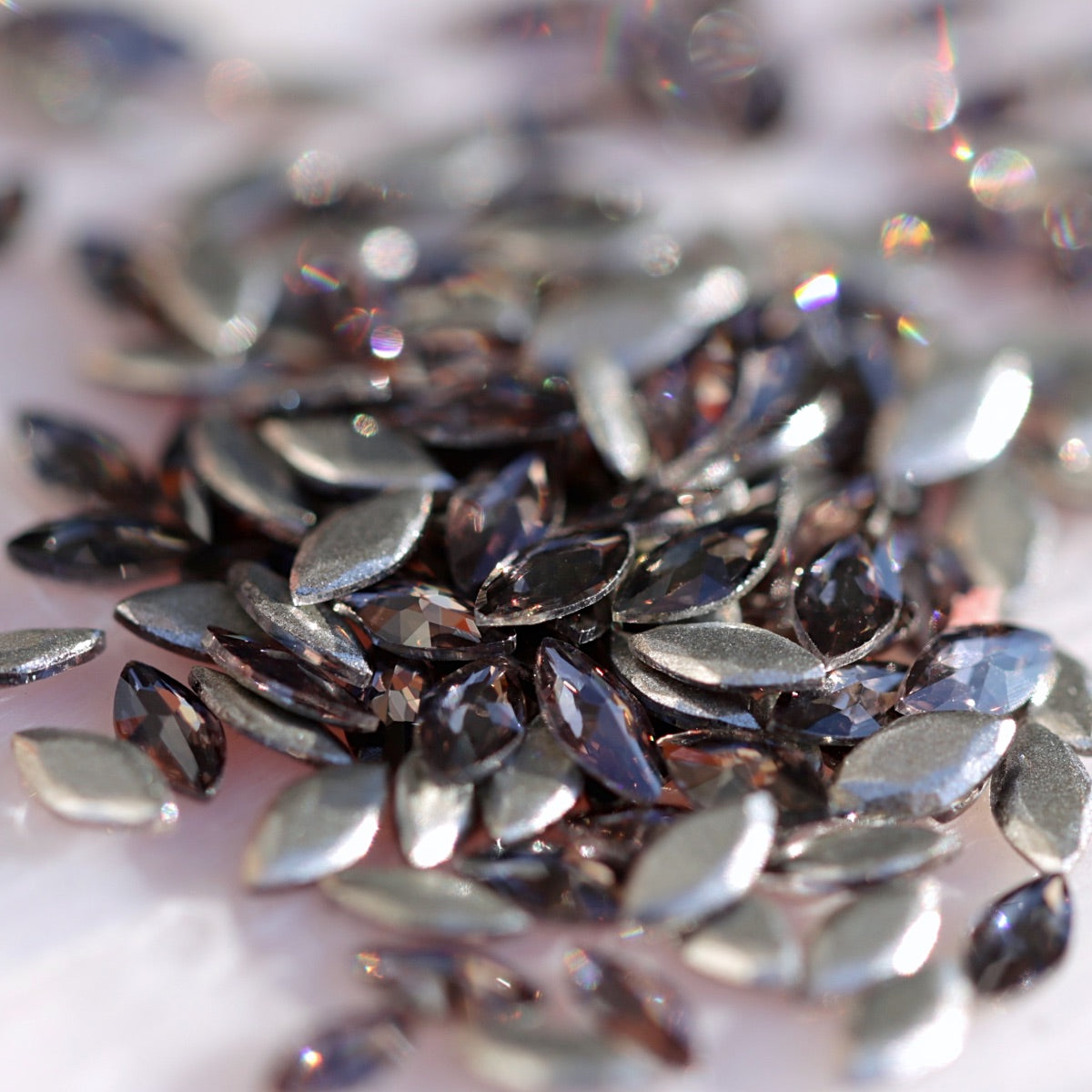 Closeup of Damson marquise flatback zircons displaying subtle purple-silver sheen and precision faceting