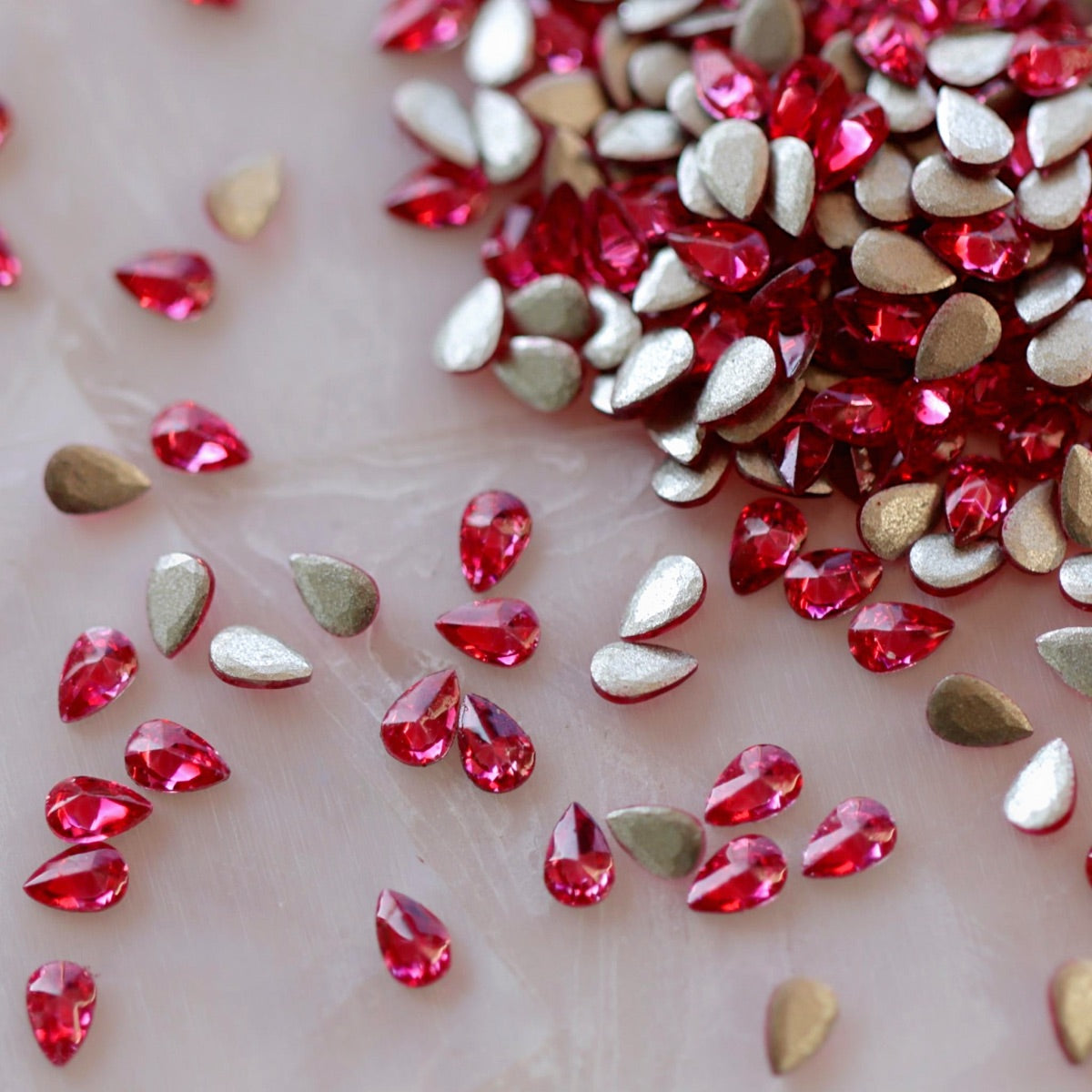 Close-up of Flatback Zircon Nail Art Drop Deep Pink crystals, highlighting the rich pink color and faceted teardrop shape perfect for detailed nail designs.