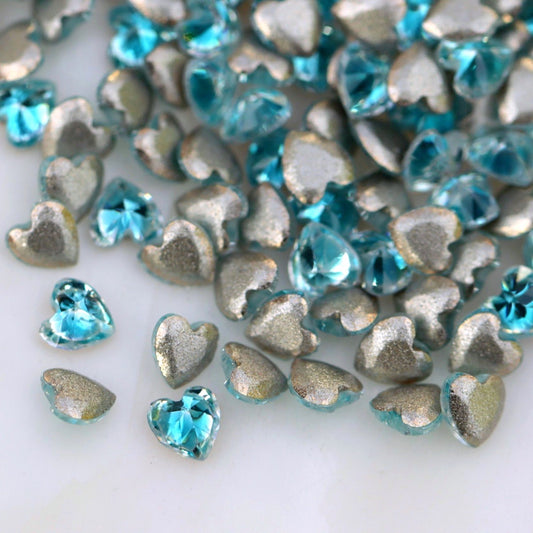 Faceted aquamarine blue heart-shaped flatback zircon nail decorations.