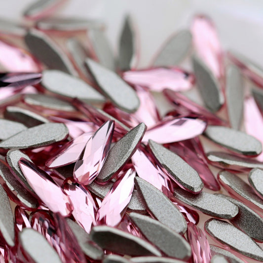 K9 Crystal Flatback Raindrop in Rose Crystal, measuring 6×2 mm. The elongated teardrop-shaped crystal has a narrow pointed tip, rounded lower end and faceted front surface. Its transparent soft pink colour reflects gentle blush, pale rose, light berry, lavender and champagne-like tones. Ideal for bridal nails, floral nail art, romantic manicures, crystal clusters and elegant nail decorations.