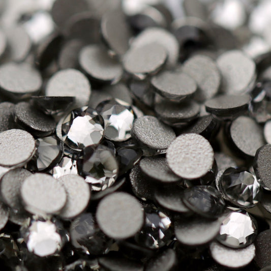 Close-up of round K9 flatback rhinestones in Black Diamond, showing sharp faceting and smoky charcoal, graphite and silver-toned reflections.