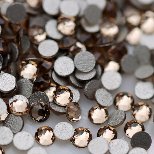 Light Colorado Topaz K9 flatback rhinestones displayed from the front and back, highlighting their reflective faceted tops and flat backs for nail-art application.