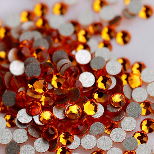 Tangerine K9 flatback rhinestones displayed from the front and back, highlighting their reflective orange faceted tops and flat backs for nail-art application.