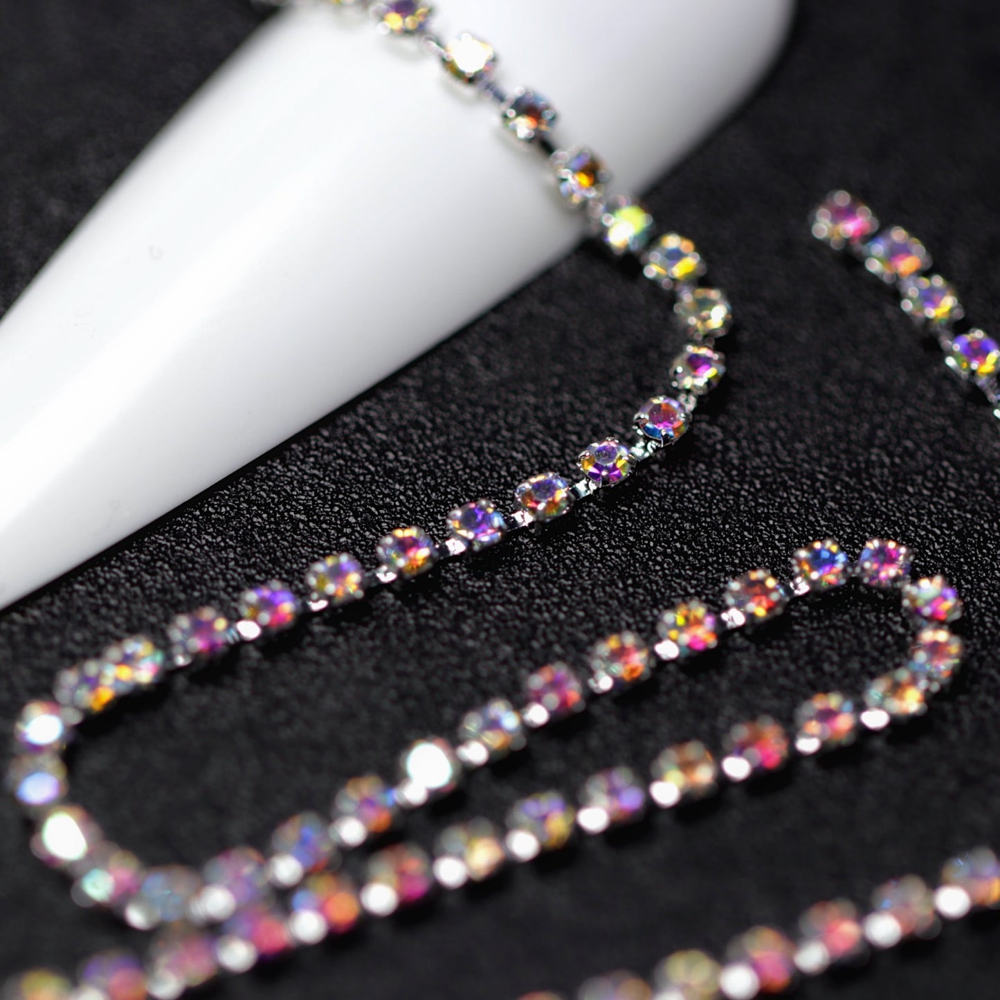 Close-up of silver 1.5 mm Crystal AB rhinestone cup chain for nail art on black background