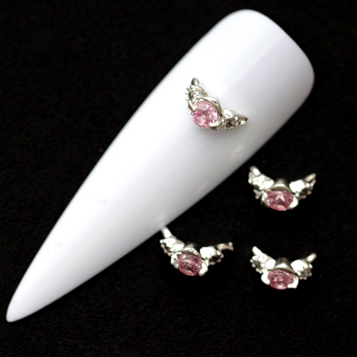 Silver 9×4 mm curved nail ring charms with central light rose CZ and small clear crystals displayed on a white nail tip against a dark background