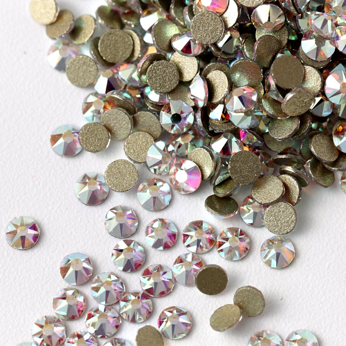 Flatback Crystal AB rhinestones with a 16-facet (8+8) cut and metallic foil backs scattered in a shimmering pile scattered on a white background.