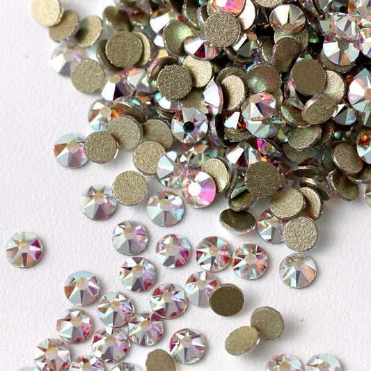Flatback Crystal AB rhinestones with a 16-facet (8+8) cut and metallic foil backs scattered in a shimmering pile scattered on a white background.