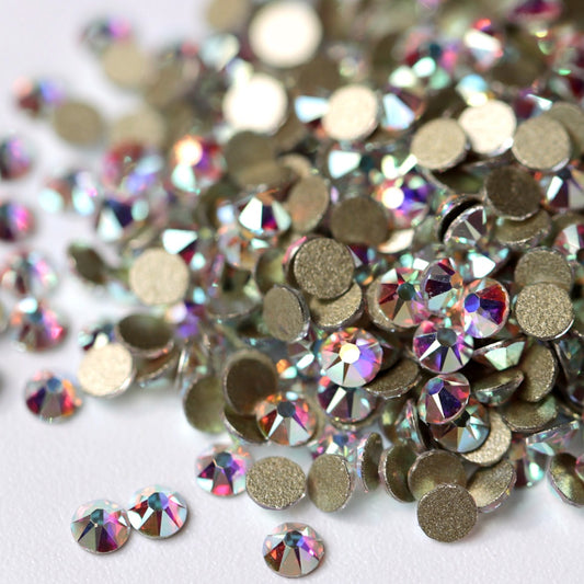 Flatback Crystal AB rhinestones with a 16-facet (8+8) cut and metallic foil backs scattered in a shimmering pile scattered on a white background.
