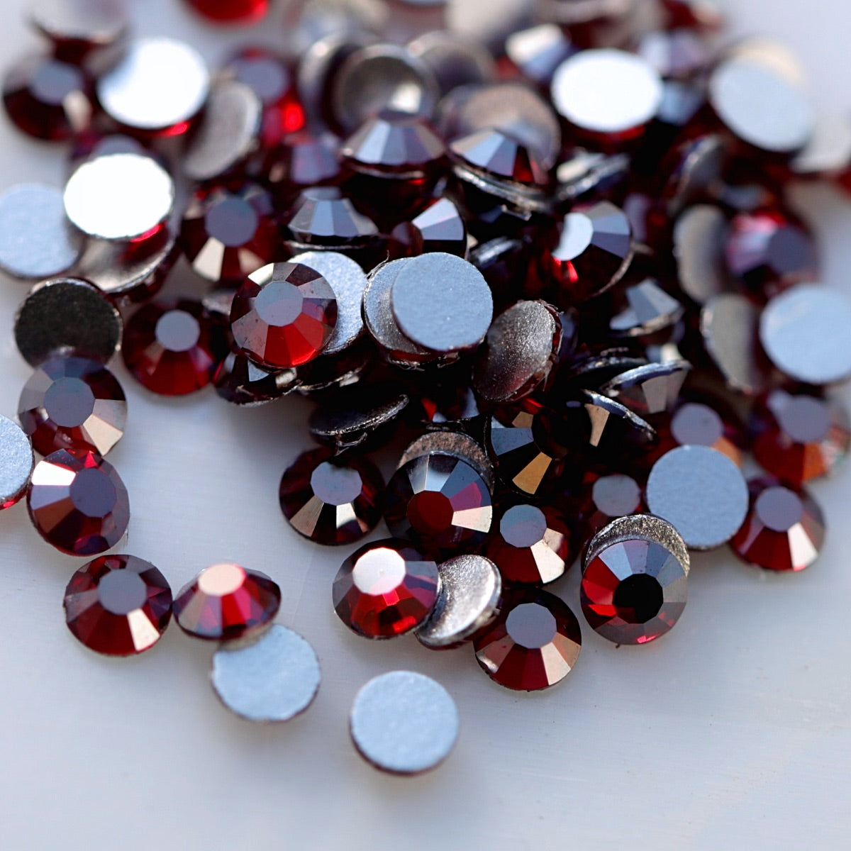 Dark Siam burgundy-red flatback rhinestones with metallic silver shimmer and reflective faceted surface.