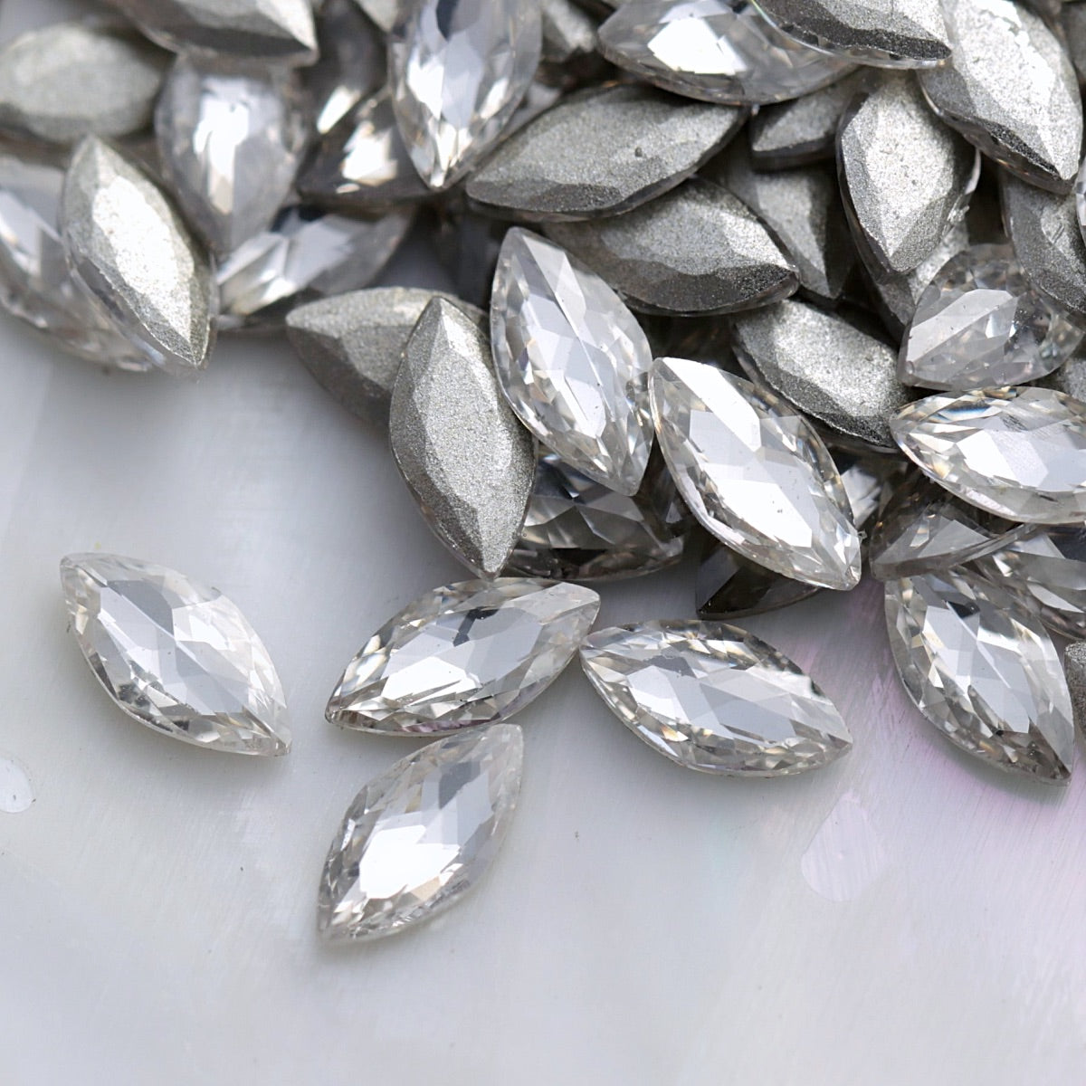 Close-up of sparkling clear marquise-shaped flatback zircon crystals with silver backs, perfect for creating elegant nail designs and crystal patterns