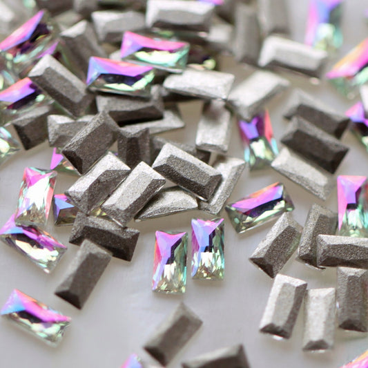 Flatback Zircon Nail Art Baguette crystals in Paradise Shine, measuring 4×2mm. The rectangular precision-faceted crystals feature shifting reflections in pink, magenta, purple, green, yellow, aqua, turquoise, blue and champagne tones. Ideal for geometric nail art, crystal French tips, colourful festival manicures, pastel designs and jewellery-inspired nail decorations.