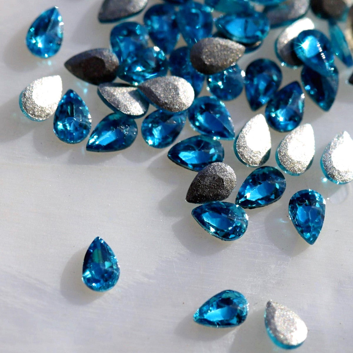 Flatback Zircon Nail Art Drop Caribbean Blue crystals measuring 3×2 mm with vivid turquoise, aqua and ocean-blue reflections.