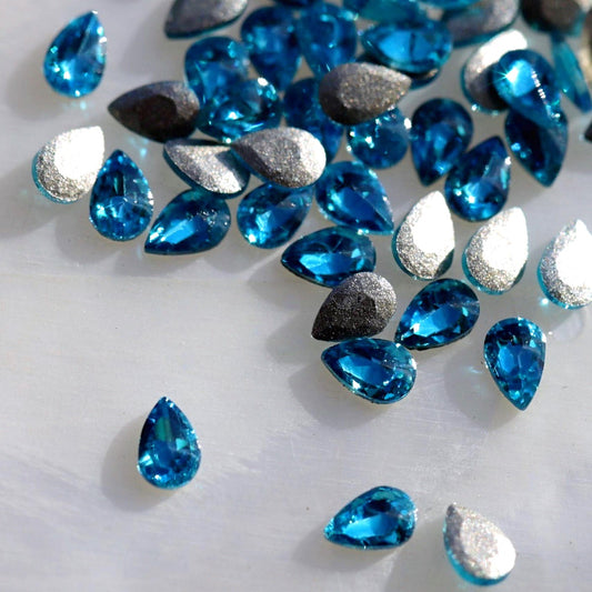 Flatback Zircon Nail Art Drop Caribbean Blue crystals measuring 3×2 mm with vivid turquoise, aqua and ocean-blue reflections.
