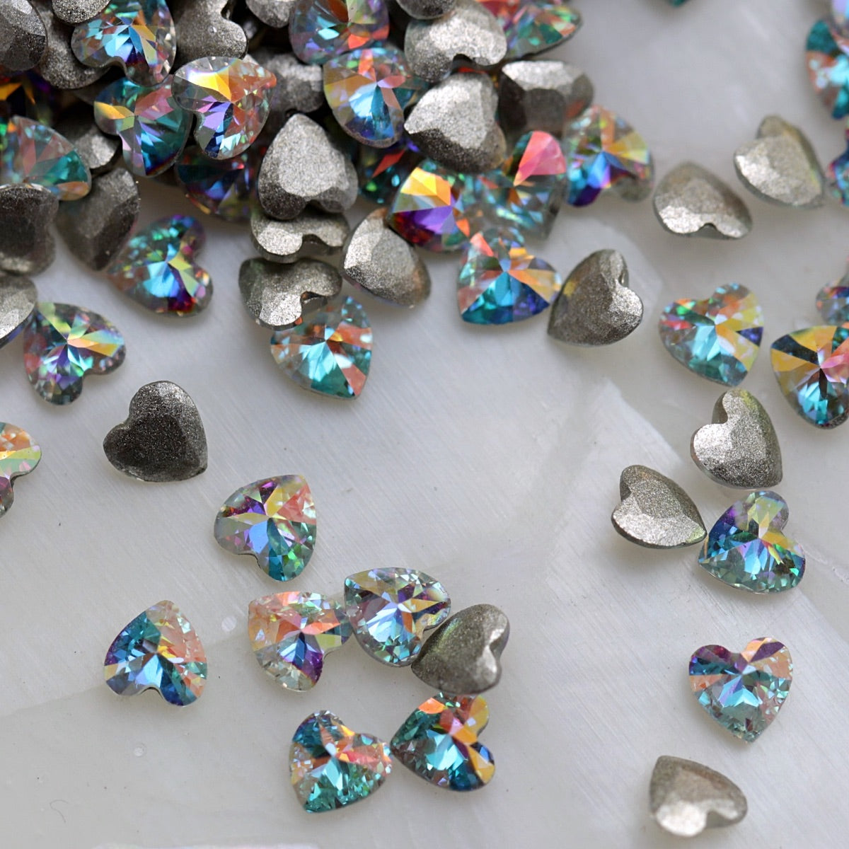 Crystal AB flatback zircon heart nail decorations with clear faceted surfaces and rainbow reflections.