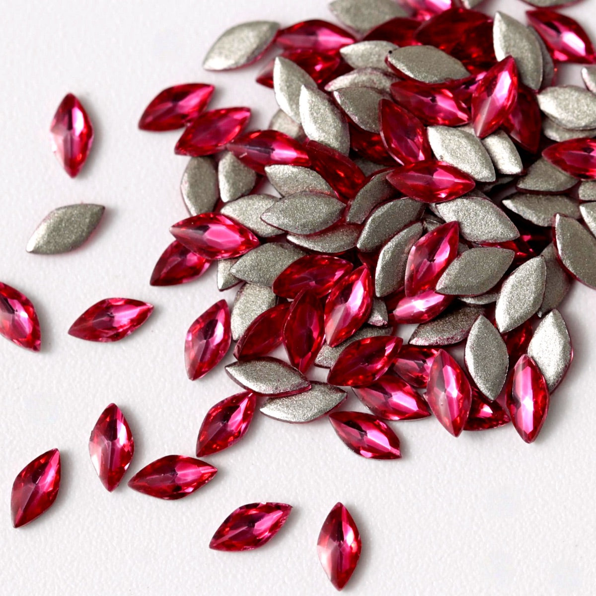 Flatback Zircon Nail Art Marquise crystals in Magenta, measuring 4×2mm. The elongated leaf-shaped crystals feature a precision-faceted surface with vivid magenta, fuchsia, hot pink, raspberry, ruby and berry reflections. Ideal for floral, romantic, glamour, festive and creative nail art designs.
