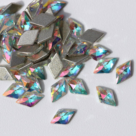 Flatback Zircon Nail Art Rhombus crystals in Crystal AB, measuring 5×3mm. The diamond-shaped crystals feature a precision-faceted transparent surface with Aurora Borealis reflections in pink, lilac, aqua, blue, turquoise, green, yellow, peach and champagne tones. Ideal for bridal nails, geometric designs, glamour manicures, mermaid nail art and luxury crystal arrangements.
