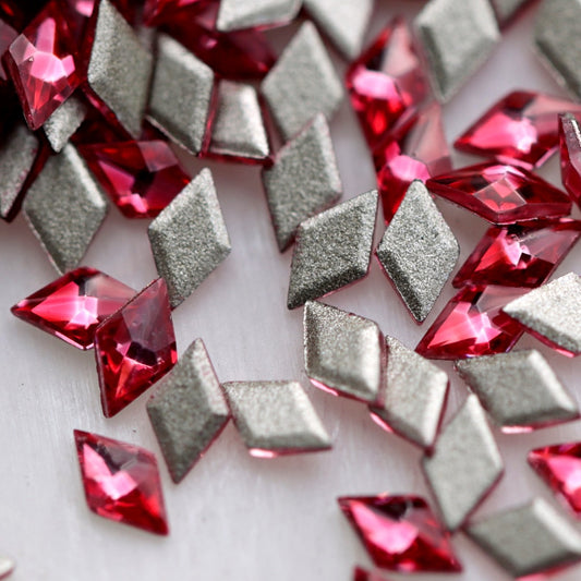 Close-up of 3.5×2mm Magenta faceted zircon rhombus stones, showing bright fuchsia, raspberry and deep red reflections with flat adhesive backs.