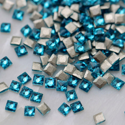 Caribbean Blue square zircon stones displayed from the front and back, highlighting their bright aqua-blue faceted surfaces and flatback design for nail-art application.