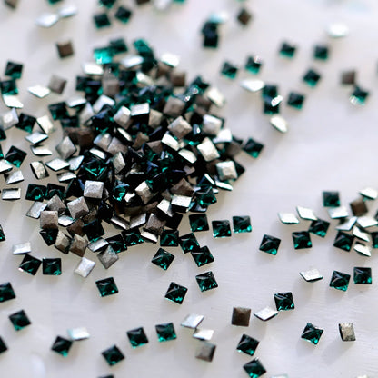 Flatback Zircon Nail Art Square crystals in Emerald, measuring 1.5mm. The tiny square-shaped crystals feature a faceted front surface with rich emerald green, forest green, jewel green and subtle teal reflections. Ideal for detailed nail art, geometric patterns, crystal borders, festive manicures and elegant nail decorations.