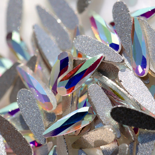 Crystal AB glass flatback raindrop crystals with a clear base and Aurora Borealis coating. Their faceted tapered shape reflects blue, pink, purple, green, gold and silver flashes, making them ideal for bridal nails, crystal flowers, mermaid designs, winter manicures and elegant nail-art accents.