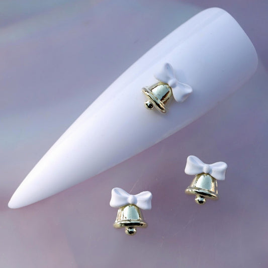 Gold-tone Christmas bell nail charm decorated with a soft white bow and a small rounded clapper. This elegant festive nail decoration is ideal for Christmas manicures, winter nail art, holiday parties, gift-inspired designs and seasonal accent nails.