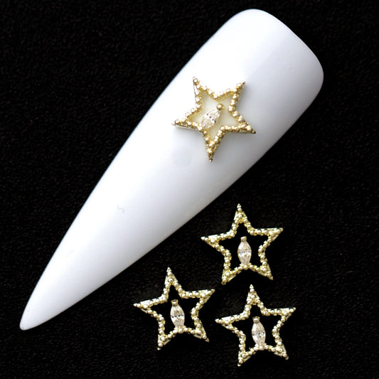 Gold 9 mm open star nail charms with central crystal CZ stone displayed on a white nail tip against a black background