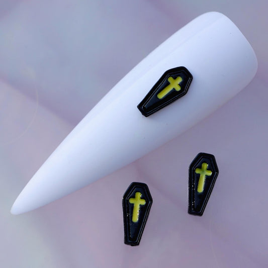 Halloween coffin-shaped nail charm with a glossy black finish, raised border details and a bright neon yellow-green cross in the centre. This gothic nail decoration is ideal for Halloween manicures, horror-inspired designs, spooky accent nails and creative seasonal nail art.