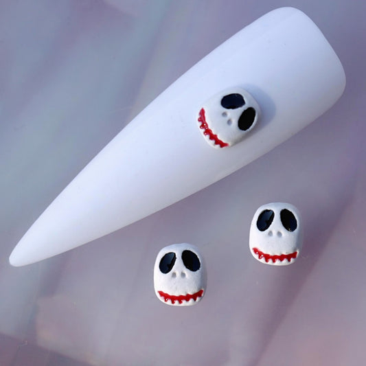 Halloween nail charm featuring the Scruffy Jack skull character. The white skull face has oversized black eyes, small nose details and a distinctive red jagged smile. This playful spooky nail decoration is ideal for Halloween manicures, horror-inspired nail art, seasonal accent nails and creative themed designs.