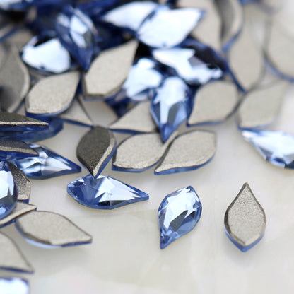 K9 Crystal Flatback Flame Light Sapphire 6×3mm with a pointed light-blue flame shape and faceted reflective surface.