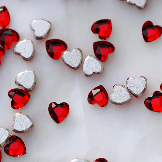 Small Siam red crystal hearts displayed from the front and back, highlighting the vivid red faceted surface and flatback design for nail-art application.