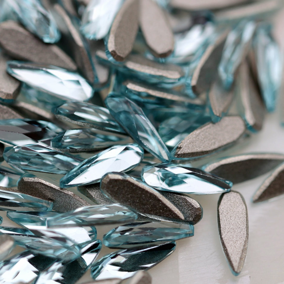 K9 Crystal Flatback Raindrop Aquamarine Crystal 6×2mm with a narrow light-blue teardrop shape and faceted reflective surface.