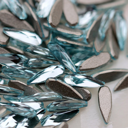 K9 Crystal Flatback Raindrop Aquamarine Crystal 6×2mm with a narrow light-blue teardrop shape and faceted reflective surface.