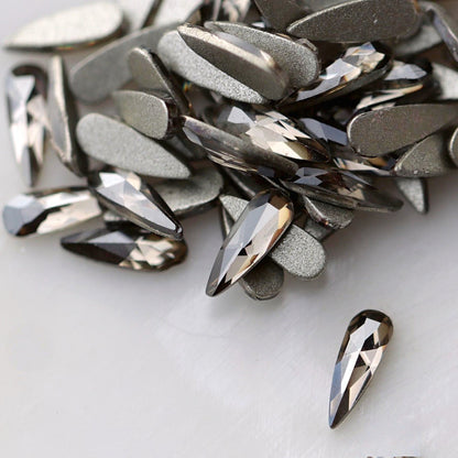 Black Diamond flatback K9 Crystal raindrops displayed from the front and back, highlighting their elongated tapered shape, reflective dark-grey facets and flat adhesive backs.