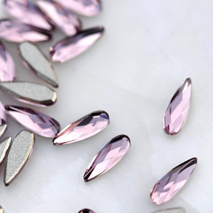 Light Amethyst flatback K9 Crystal raindrops displayed from the front and back, highlighting their elongated tapered shape, soft purple faceted surface and flat adhesive backs.