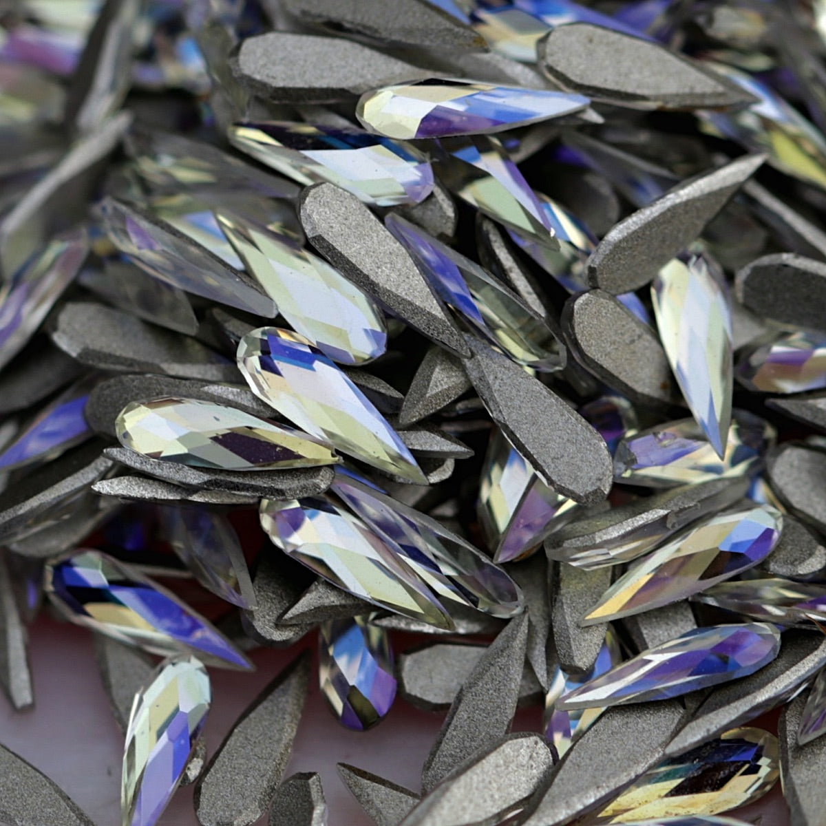 K9 Crystal flatback raindrop in Moonlight color in sharp focus on top of other stones, displaying soft ivory, lilac and blue tones