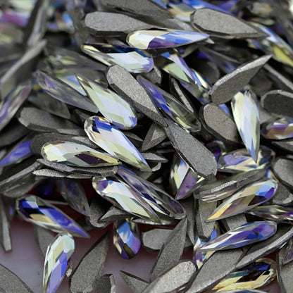 K9 Crystal flatback raindrop in Moonlight color in sharp focus on top of other stones, displaying soft ivory, lilac and blue tones