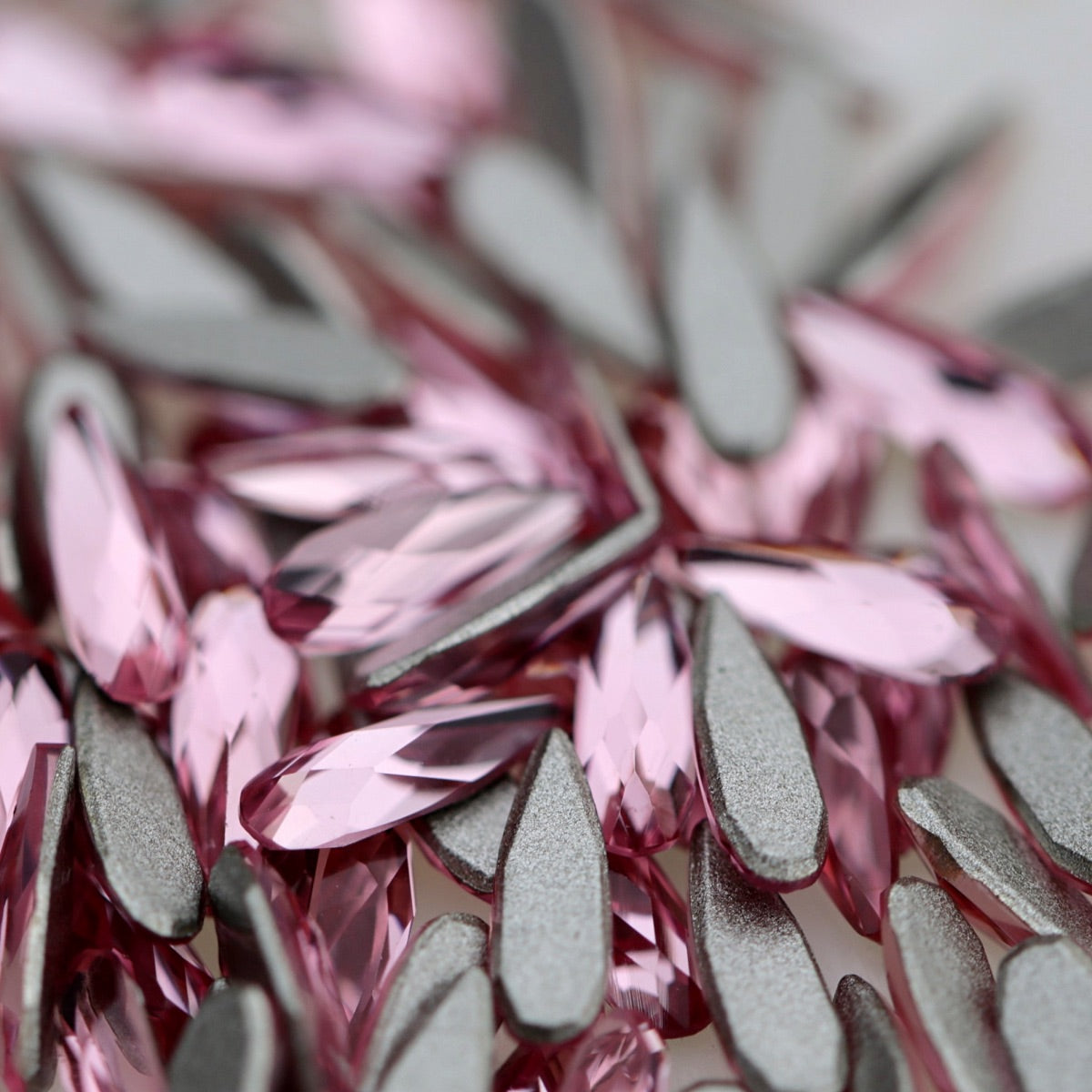 K9 Crystal Flatback Raindrop Rose Crystal 6×2 mm with a narrow pink teardrop shape and faceted reflective surface.