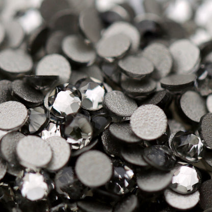 Close-up of round K9 flatback rhinestones in Black Diamond, showing sharp faceting and smoky charcoal, graphite and silver-toned reflections.