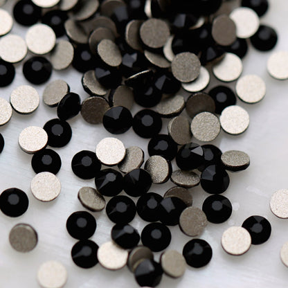 Jet black K9 flatback rhinestones displayed from the front and back, highlighting their glossy dark reflective facets and flat backs for nail-art application.