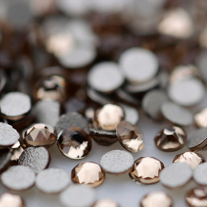 Close-up of round K9 flatback rhinestones in Light Colorado Topaz, showing sharp faceting and transparent pale topaz, champagne and warm golden reflections.