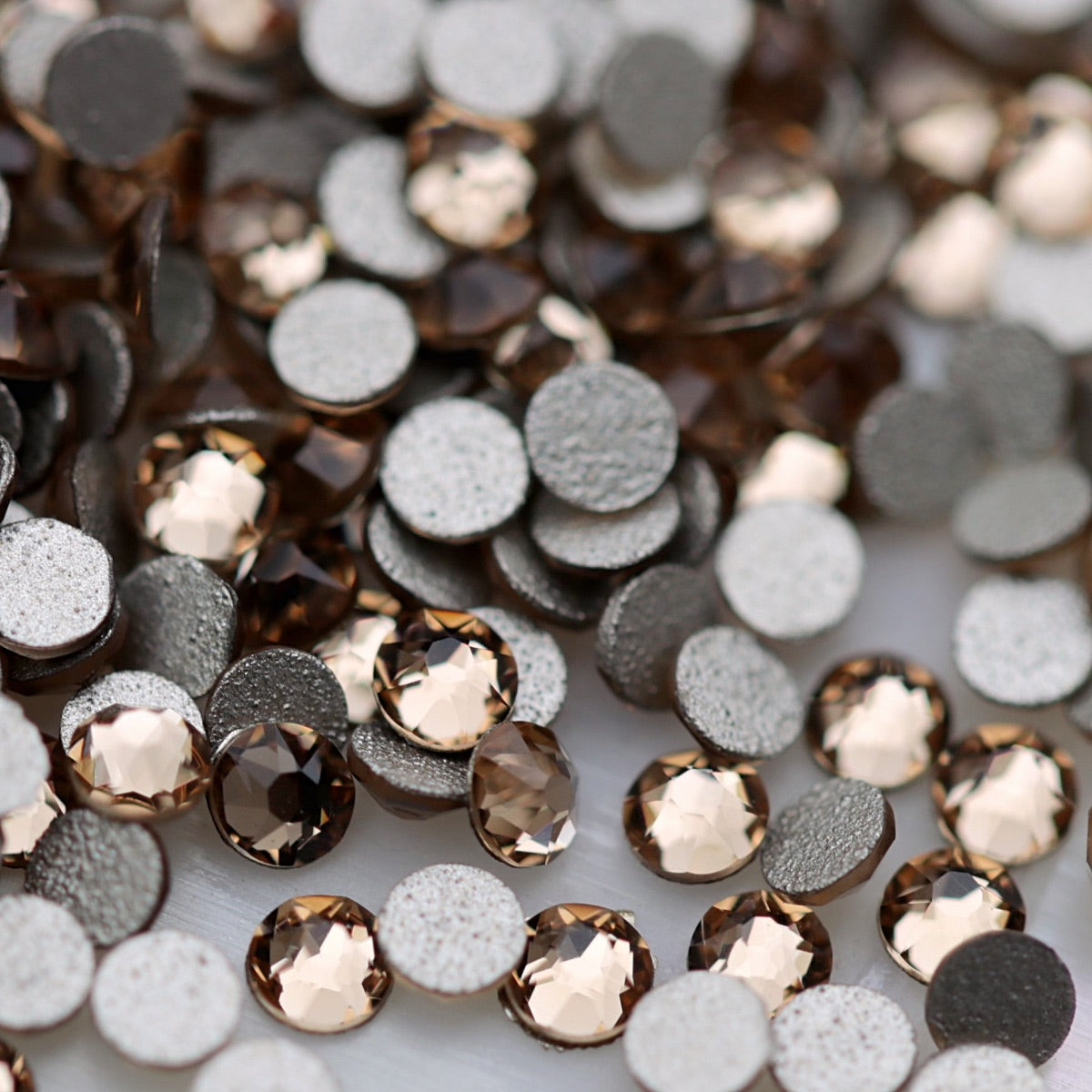 Light Colorado Topaz K9 flatback rhinestones displayed from the front and back, highlighting their reflective faceted tops and flat backs for nail-art application.