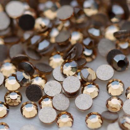 Close-up of round K9 flatback rhinestones in soft Light Peach, showing sharp faceting and warm champagne, beige and pale golden reflections.