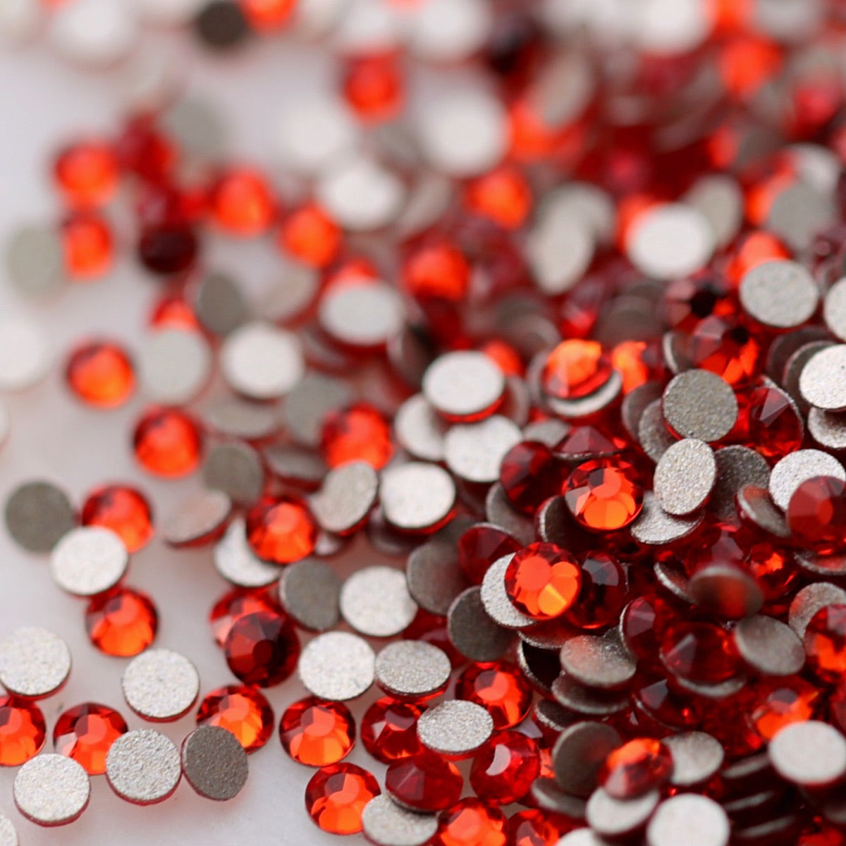 Light Siam red K9 flatback rhinestones displayed from the front and back, highlighting their reflective faceted tops and flat backs for nail-art application.