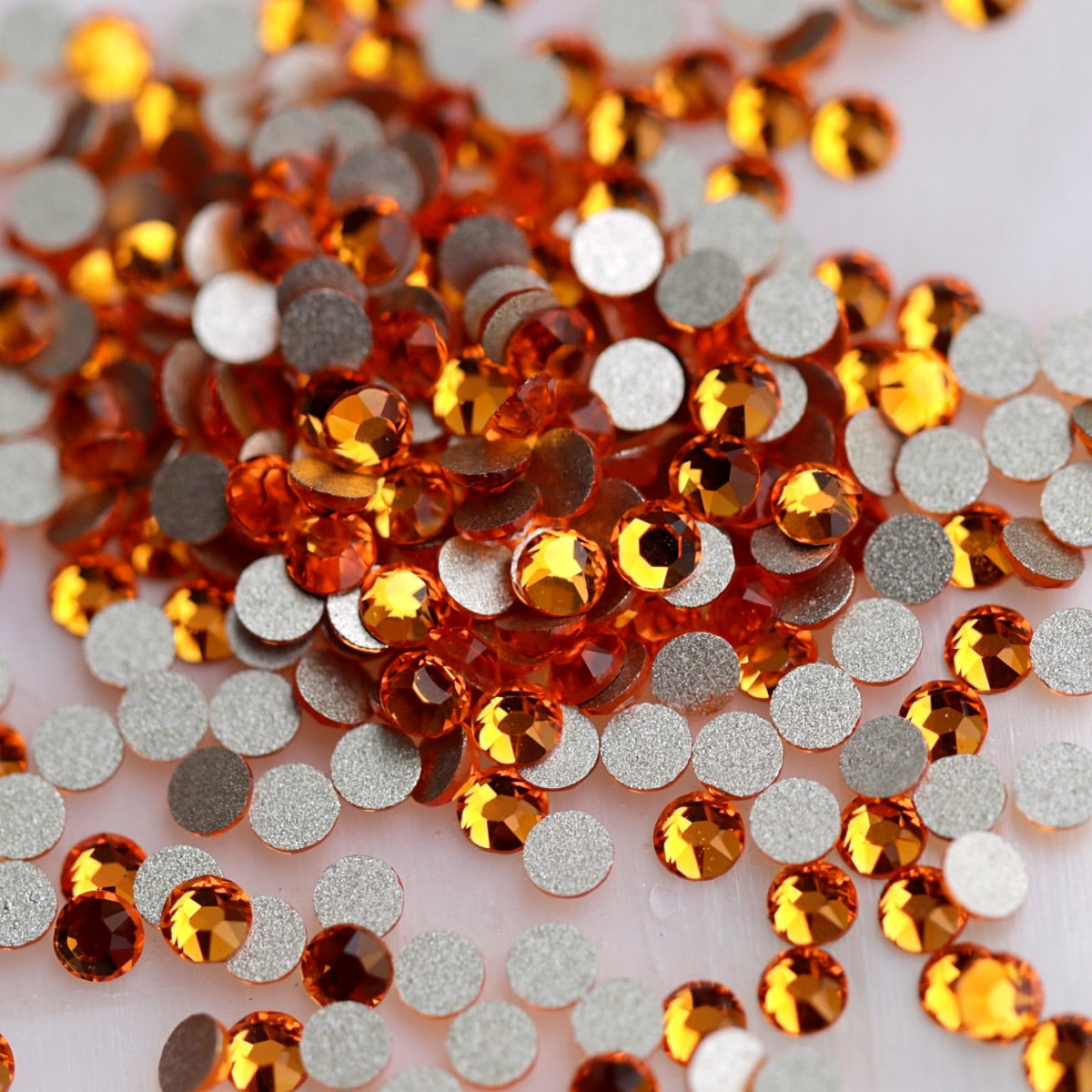 Faceted K9 flatback rhinestones in vivid Tangerine orange with bright citrus, amber and golden sparkle for nail art.