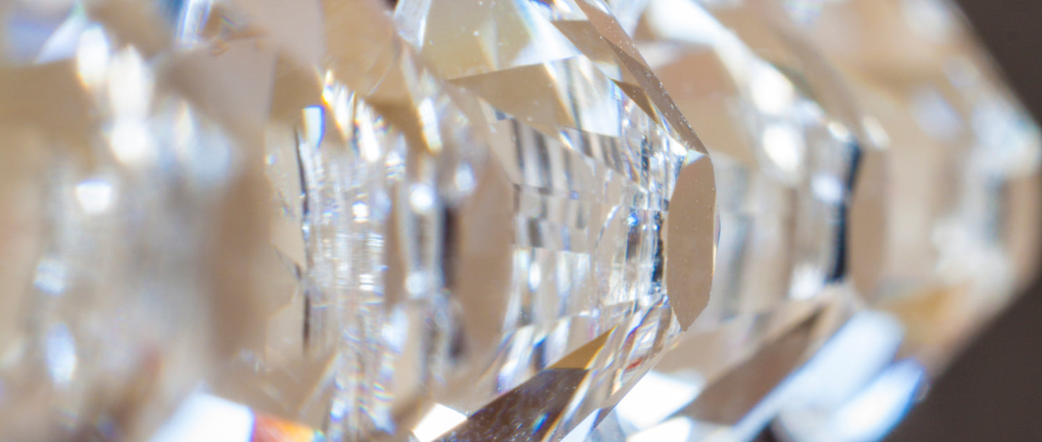 Extreme close-up macro photo of clear Preciosa flatback crystal rhinestones, showing their brilliant facets and sparkle for nail art, fashion embellishments and craft projects