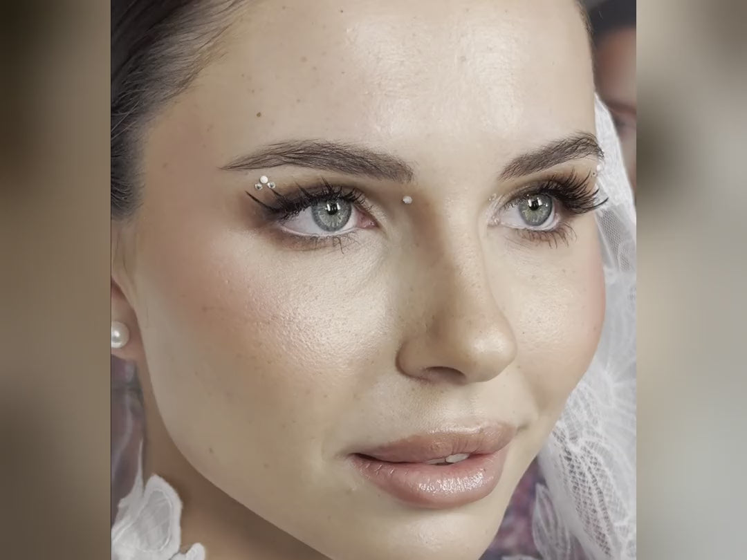 Makeup artist applying Swarovski crystals and pearl face gems around a model's eyes during a bridal makeup workshop