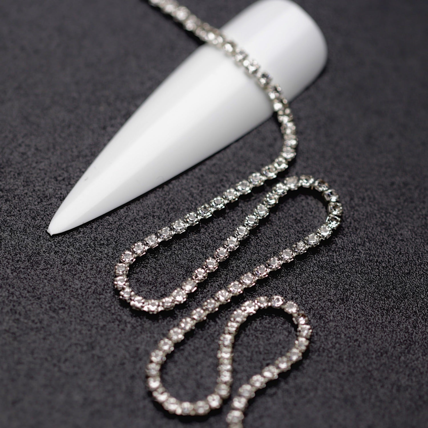 Close-up of silver 1.5 mm clear crystal rhinestone cup chain for nail art on black background